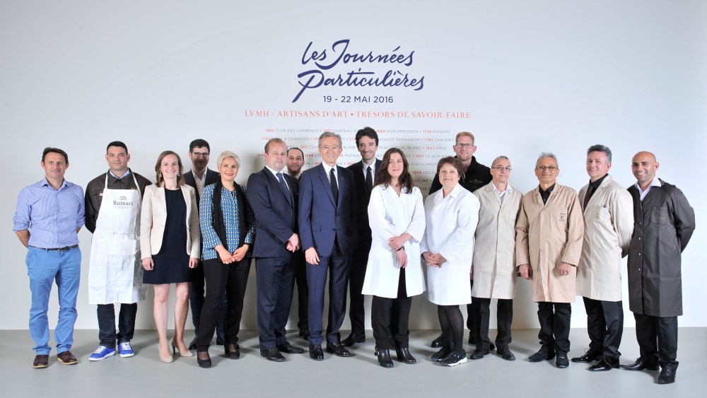 Antoine and Bernard Arnault posing with the group of artisans