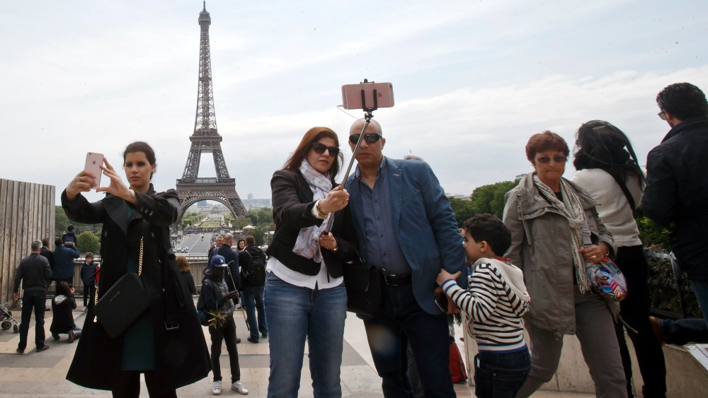 Tourists take selfies at Trocadero Plaza next to the Eiffel tower in Paris.