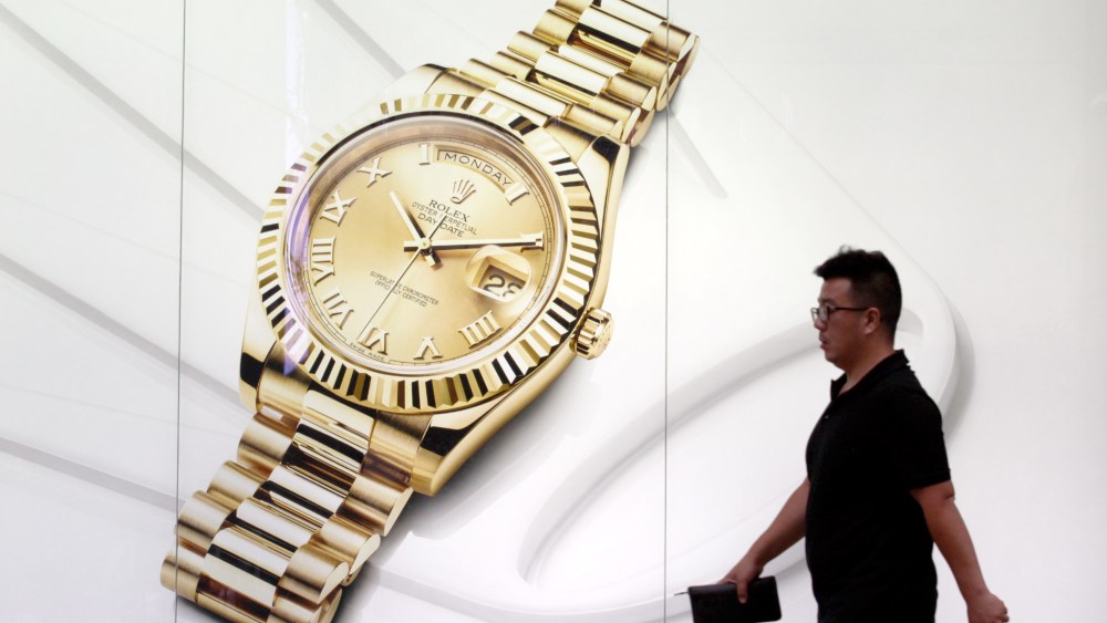 A pedestrian walks past an advertisement for Rolex watches in China.