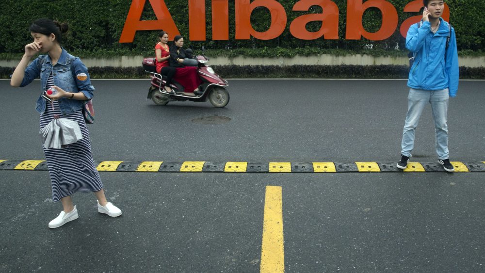 Workers stand near the company logo at the Alibaba Group headquarters in Hangzhou, China.