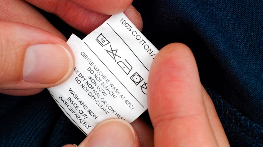 Woman hands holding clothes label with cleaning instructions
