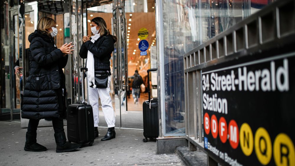 Shoppers wear face masks and sanitize their hands on the sidewalk at Herald Square in New York.