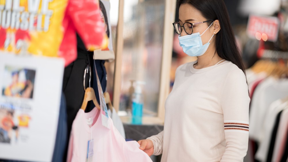 woman shopping clothes rack mask glasses