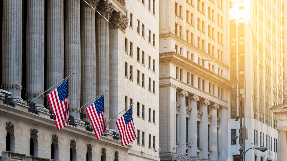American flags flying in front of the historic buildings of Wall Street in the financial district of Manhattan, New York City NYC