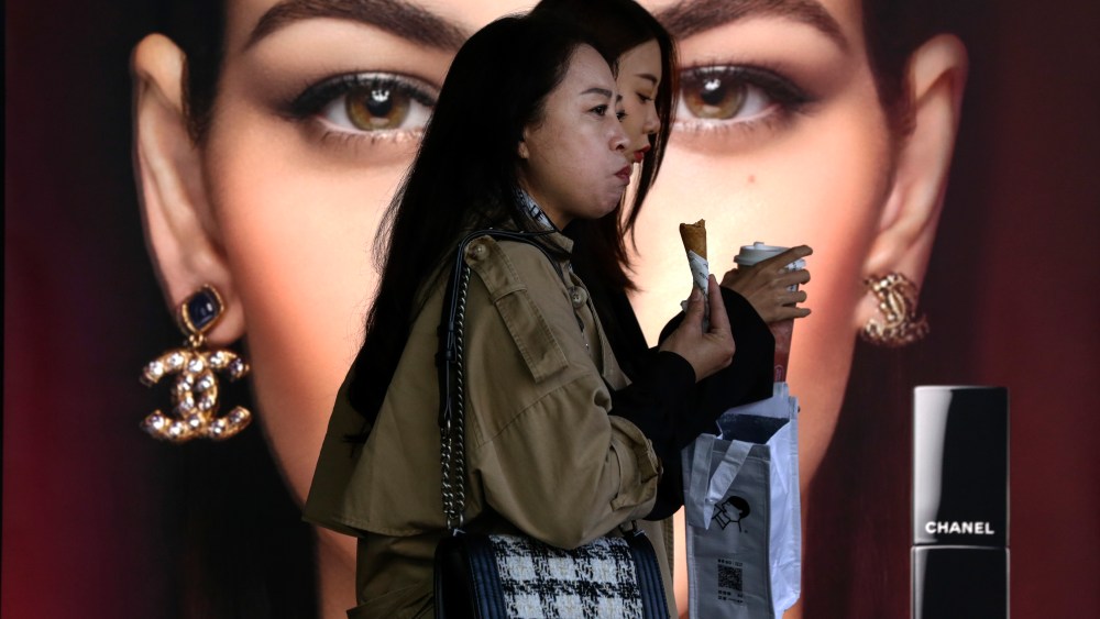 Women pass by a Chanel advertisement in Beijing.