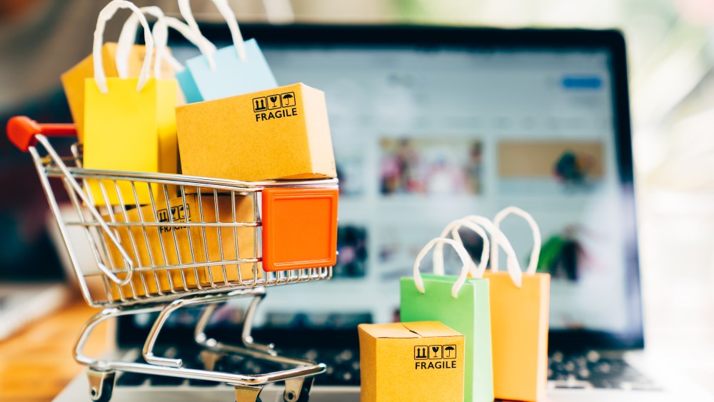 Product package boxes and shopping bag in cart with laptop computer which web store shop on screen for online shopping and delivery concept