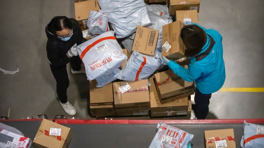 Workers load parcels onto a conveyor belt at a JD.com warehouse in Beijing, Wednesday, Nov. 11, 2020.