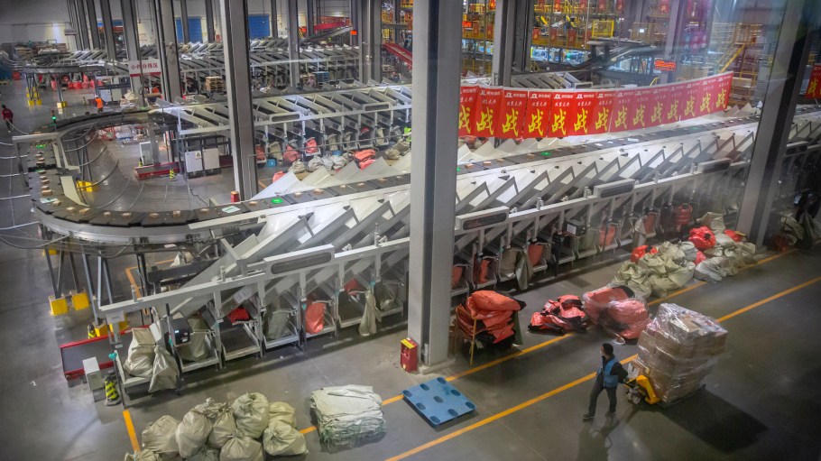 An employee walks past an automated parcel sorting machine at a warehouse for online retailer JD.com in Beijing, Wednesday, Nov. 11, 2020.