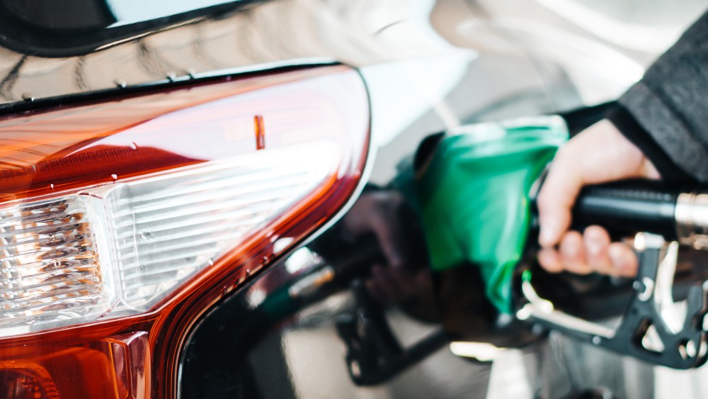 Man pumping petrol at gas station into vehicle. Hand holding a p