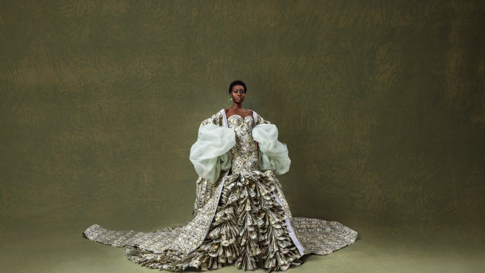 Fe Noel debuts “the Dre$$” as the closing piece of its spring 2023 runway show. The couture strapless gown with ruffled petticoat and robe with 16-foot cathedral train is made of $1.6 million worth of artificial U.S. dollars.