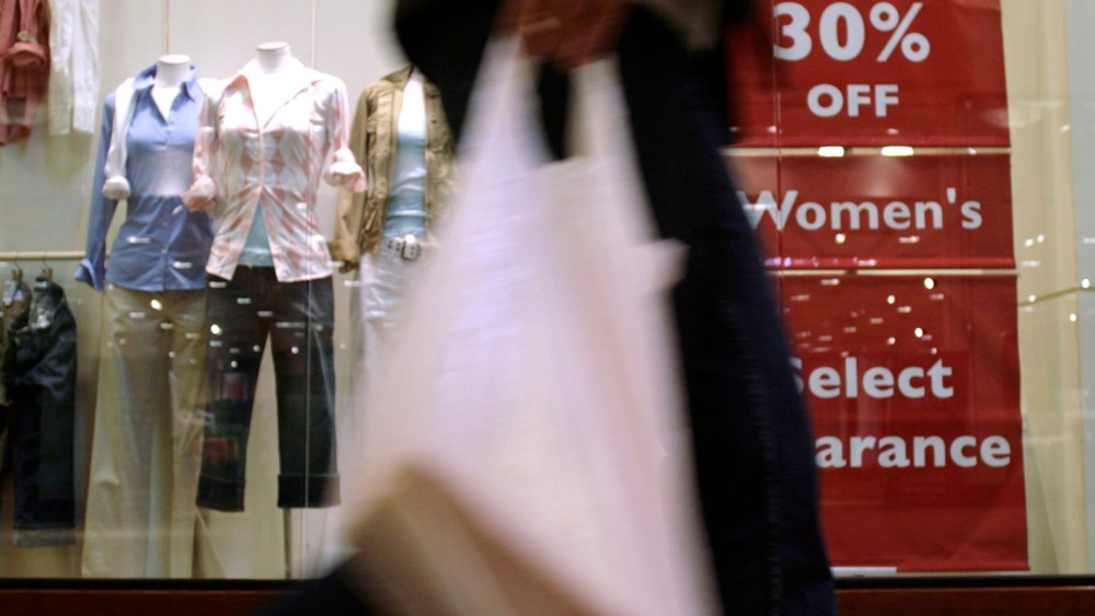 With bag in hand, an unidentified shopper whisks past signs promoting sales next to the window displays of goods available at a clothing store in a mall in the west Denver suburb of Lakewood, Colo., on Tuesday, April 17, 2007. A barometer of future economy growth rose a tepid 0.1 percent in March, hinting that the U.S. should expect only a meager economic expansion in the coming months, a private research group said Thursday, April 19, 2007. (AP Photo/David Zalubowski)