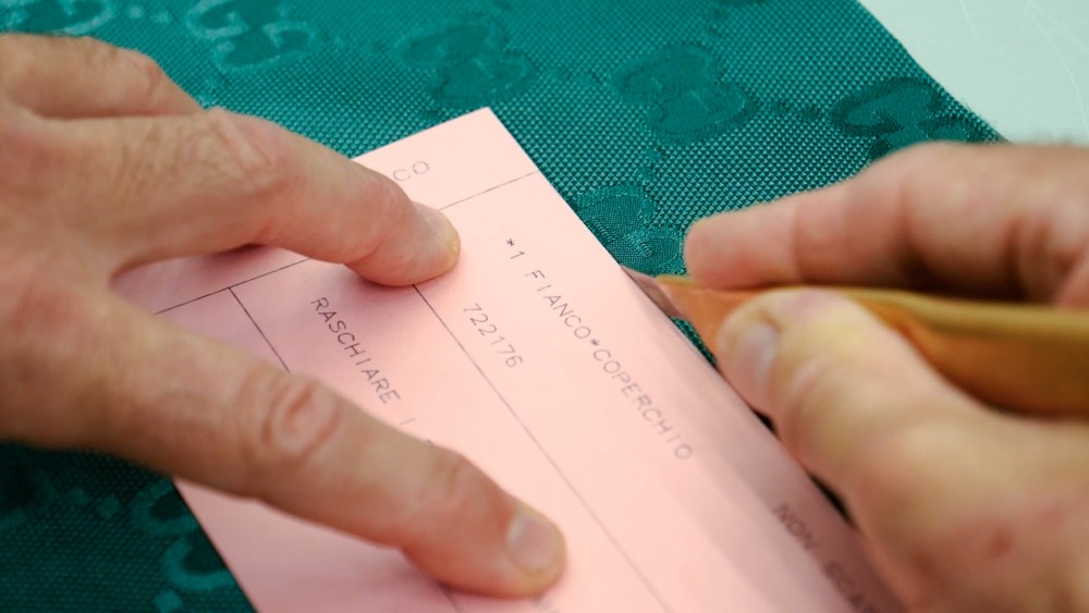 A Gucci artisan cutting a monogram-bearing Econyl textile.
