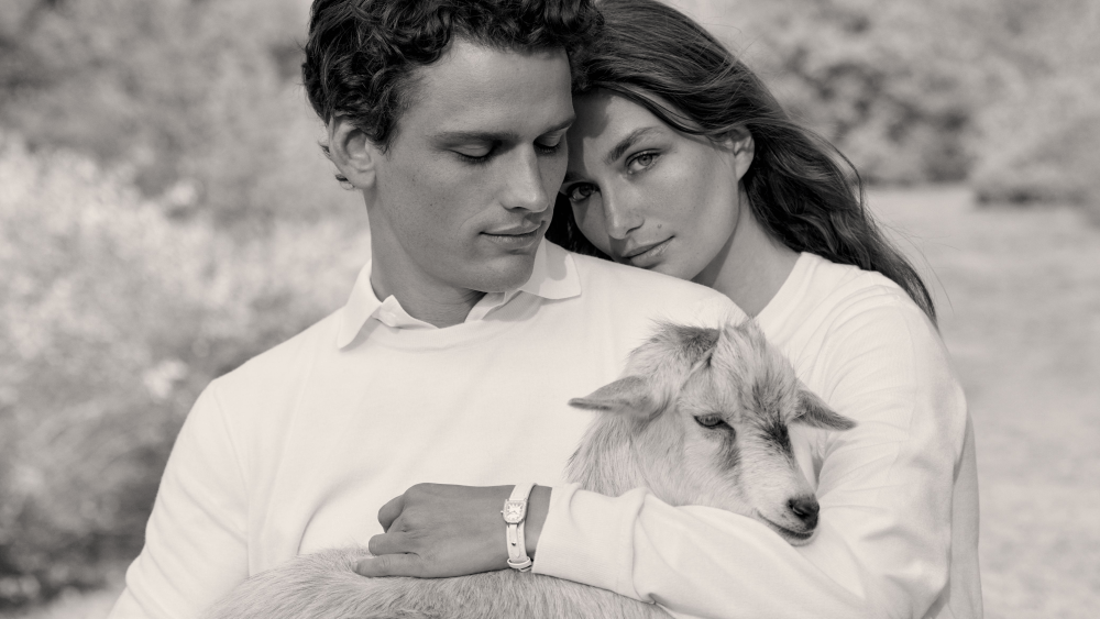 A black-and-white image of models embracing in Ralph Lauren white cashmere and holding a goat.