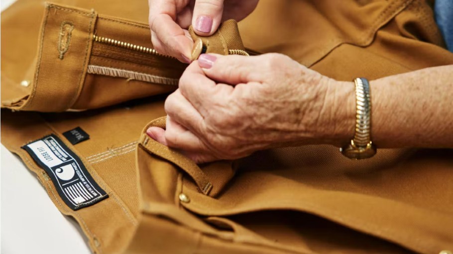 A worker replaces a button on Carhartt pants.