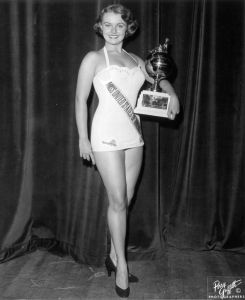 July 1953:  Full-length portrait of Myrna Hansen, Miss United States of America and second runner-up in the Miss Universe Pageant, holding a trophy while wearing a swimsuit and high heels, Long Beach, California.  (Photo by Hulton Archive/Getty Images)