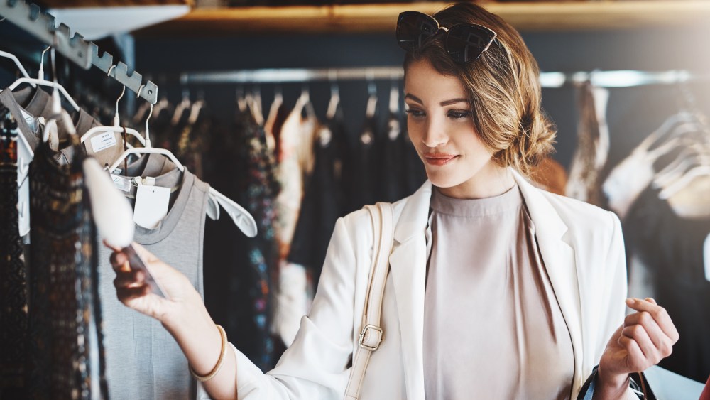 Shopping, fashion and woman with a sale, boutique and discount items with retail, client and luxury. Female person, customer and shopper with price tag, store and outfit choice with clothes selection.