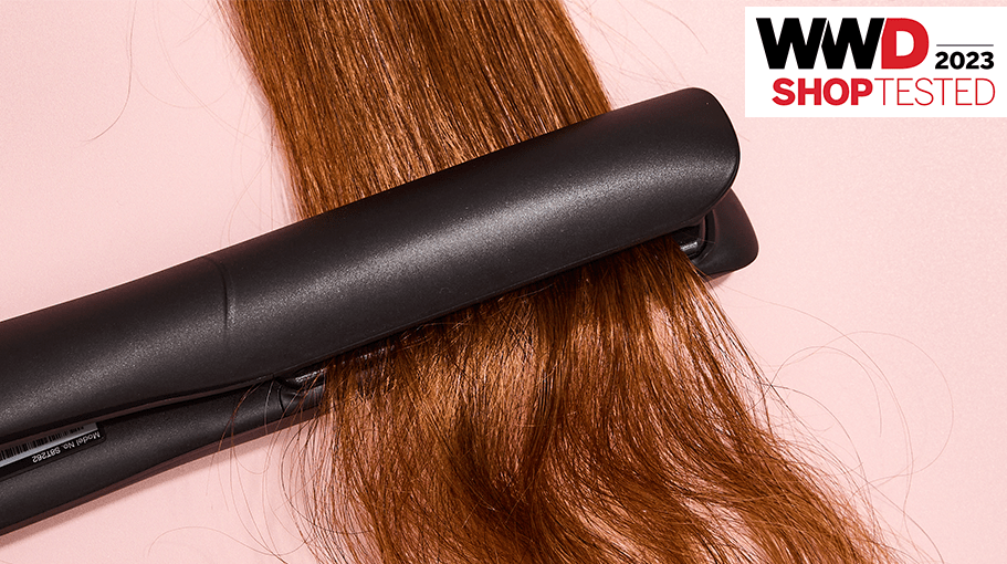 hair straightener on brown hair and a pink background