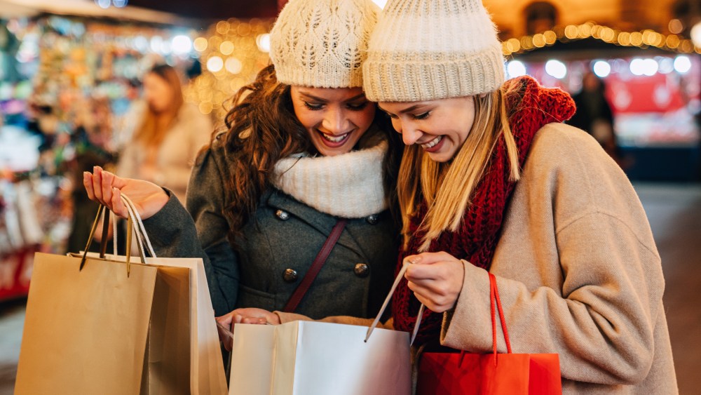 Christmas sale and people concept. Happy young women friends with shopping bags enjoying shopping in christmas market