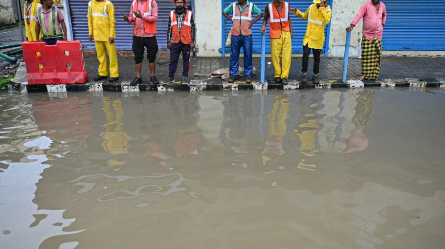 Men stand over a pavement along a flooded street following rainfall, as cyclone Michaung is expected to make landfall, in Chennai on Dec. 3, 2023.