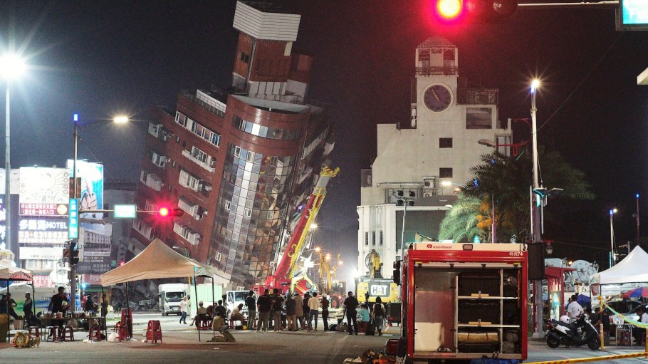 Emergency personnel stand in front of a partially collapsed building leaning over a street in Hualien on April 3, 2024, after a major earthquake hit Taiwan's east. At least 10 people were killed and more than 1,000 injured on April 3 by a powerful earthquake in Taiwan that damaged dozens of buildings and prompted tsunami warnings that extended to Japan and the Philippines before being lifted.