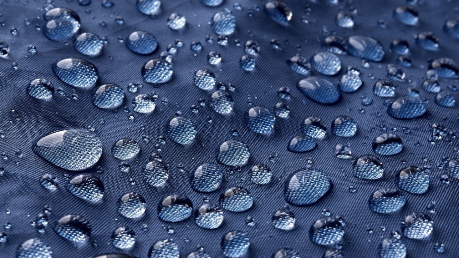 Rain water droplets on blue fiber waterproof fabric.