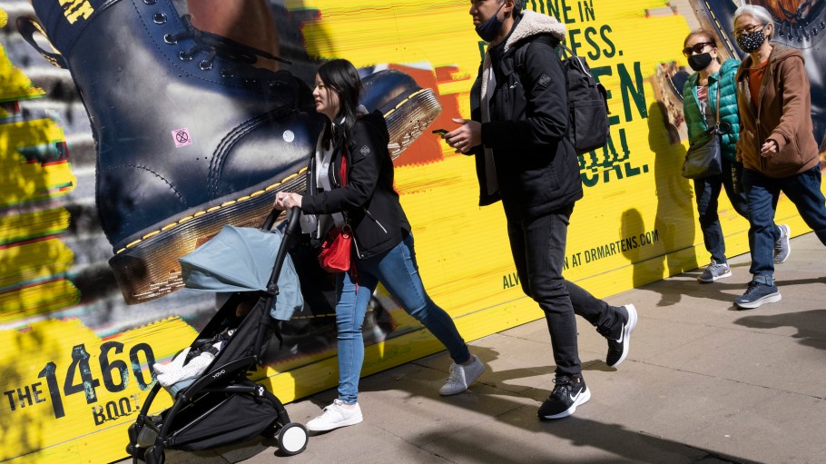 Shoppers walk past a hoarding for the Doc Martens footwear brand on London's Oxford Street in April 2022.