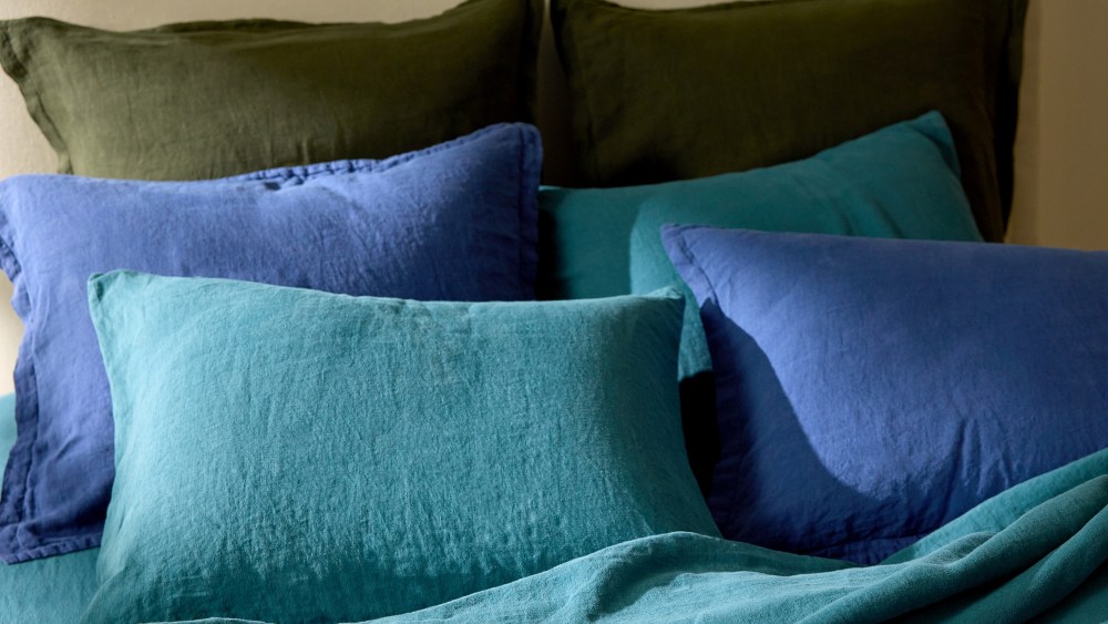 six pillows resting on a bed, enveloped by pillowcases in earthy and blue tones
