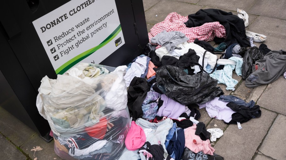 Items of clothing lay damp on the ground beneath a Traid charity shop bin, on the Hornsey Road in north London, on 18th March 2024, in London, England.