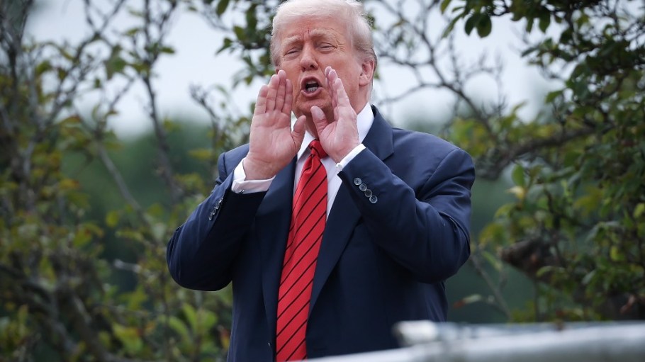 President Donald Trump shouts answers to questions from reporters as he tours the roof of the White House on Tuesday.
