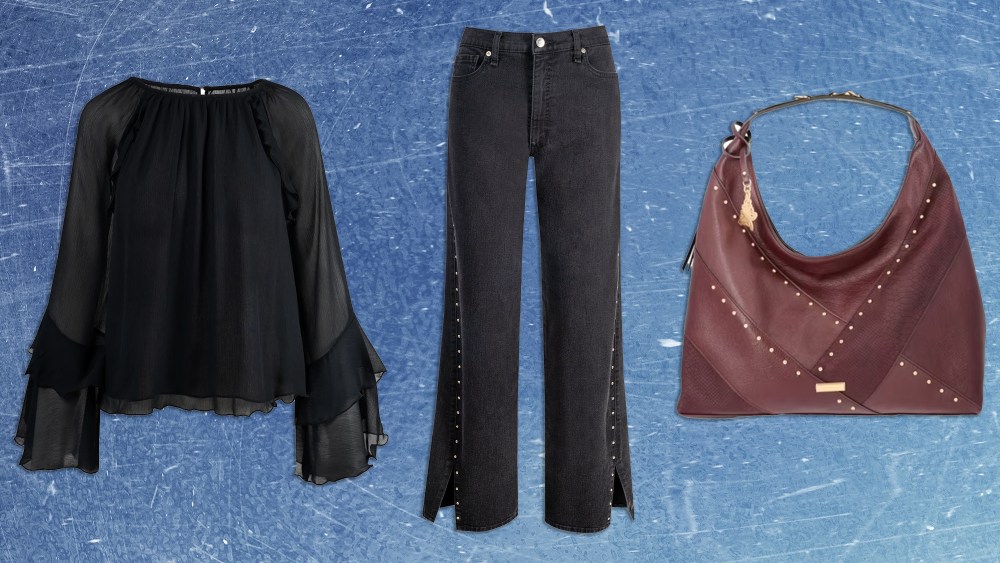 flowy black blouse, black studded jeans, and slouchy bag over distressed blue background