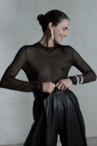 Michael Kors Collection nylon and viscose bodysuit; Ralph Lauren Collection leather pants; David Yurman High Jewelry Floating Diamonds ring in 18-karat white gold with diamonds; Bourcheron 18-carat white gold Quatre Radiant Edition pendant earrings; David Yurman High Jewelry Floating Diamonds Helena bracelet in 18-karat white gold with diamonds; Piaget 18-karat white gold Possession bangle. “Perlée signature” bracelet set in 18-karat white gold by Van Cleef & Arpels and “Perlée clovers” bracelet featuring diamonds set in 18-karat white gold; Clash de Cartier bracelet, 18-karat white gold; Chanel Coco Crush bracelet in 18-karat white gold.