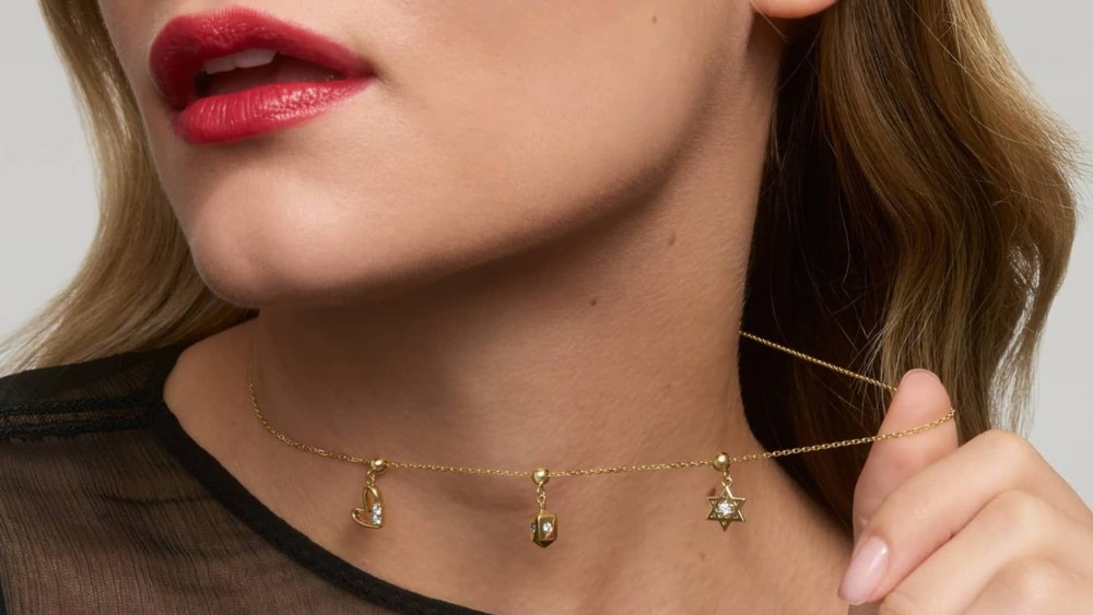 james allen holiday charms arranged on a necklace chain, modeled by a woman wearing bright red lipstick